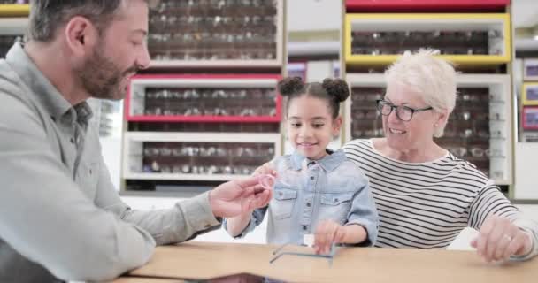 Junges Mädchen wählt Brille beim Optiker — Stockvideo