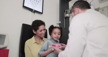 Optometrist bir çocuğa göz açıklayan