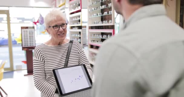 Tevreden klant betalen voor glazen bij opticien — Stockvideo