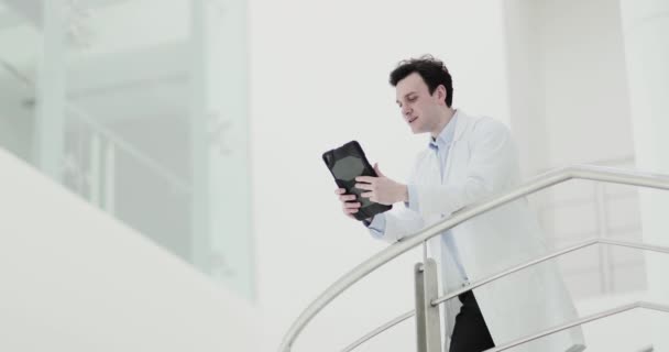 Médico masculino en el hospital mirando los resultados de la prueba en una tableta digital — Vídeos de Stock