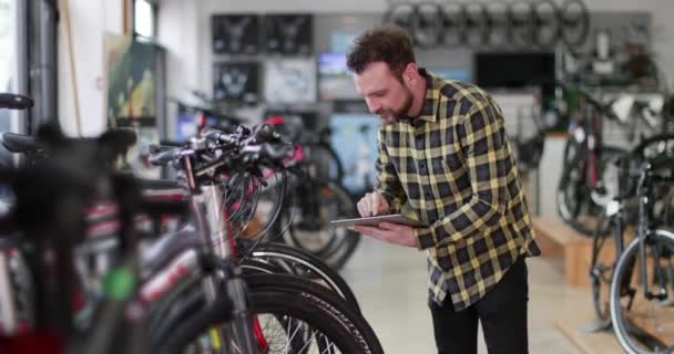 Retrato de un propietario de una pequeña empresa usando tableta digital en una tienda de bicicletas — Vídeos de Stock