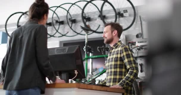 Eigenaar van kleine bedrijven die klant in een fietsenwinkel bedient — Stockvideo