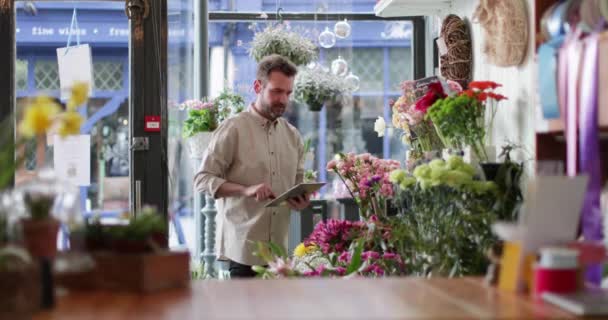 Владелец малого бизнеса с помощью цифрового планшета в флористе — стоковое видео