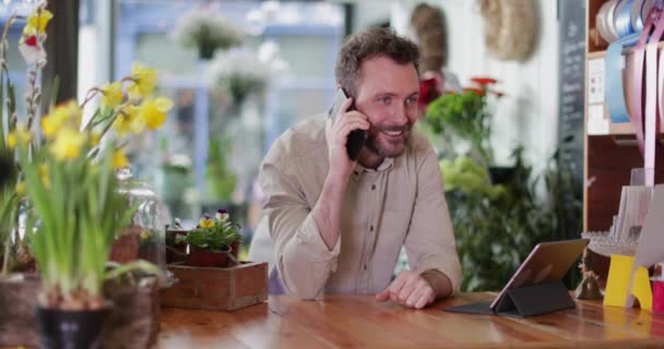 Small business owner using digital tablet and smartphone in a florist — Stock Video