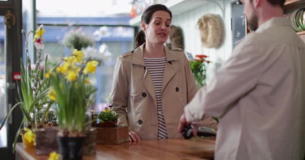 Erwachsene Frau bezahlt mit Kreditkarte im Blumenladen — Stockvideo