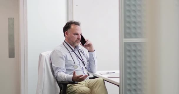 Stressed Medical Doctor on phone in his office — Stock Video