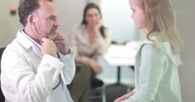 Erkek Tıp Doktoru çocuğun kalp atışlarını dinliyor