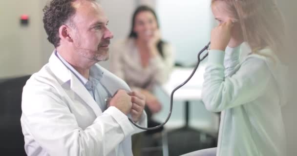 Male Medical Doctor listening to child's heartbeat — Stock Video