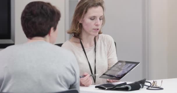 Vrouwelijke medische arts die de scanresultaten aan de patiënt uitlegt — Stockvideo