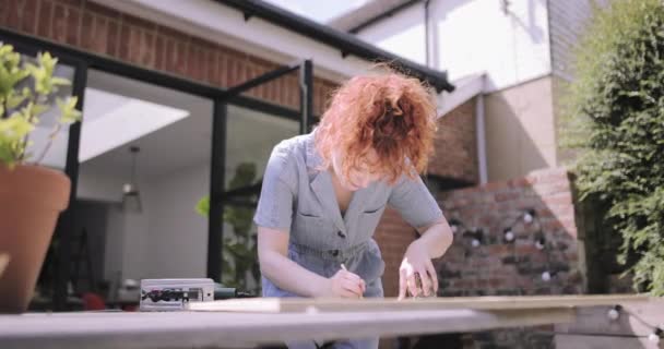 Молодая взрослая женщина делает столярное дело DIY на патио — стоковое видео