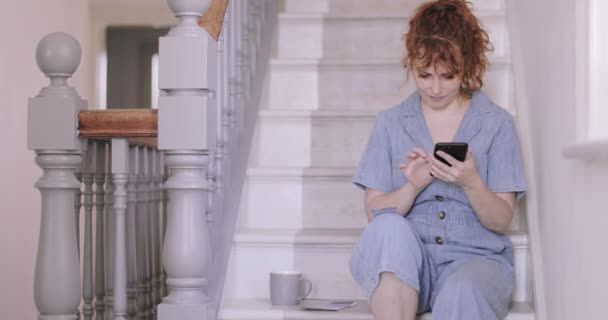 大人女性で新しい家を見ますで装飾のアイデア上のスマートフォン — ストック動画