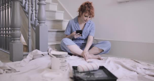 Yeni evde yetişkin bir kadın akıllı telefondaki dekorasyon fikirlerini araştırıyor. — Stok video