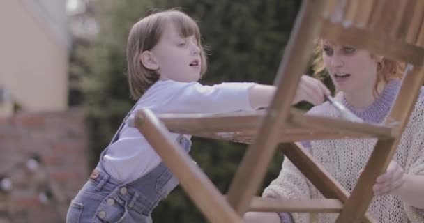 Mother painting chair with daughter in garden — Stock Video