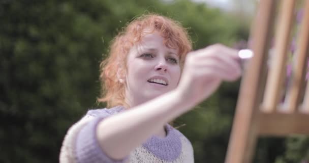 Jonge volwassen vrouw schilderen stoel in de tuin op een zomerdag — Stockvideo