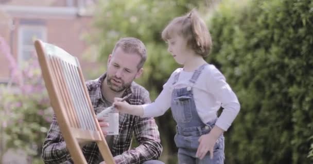 Padre pintando silla con hija en el jardín — Vídeos de Stock
