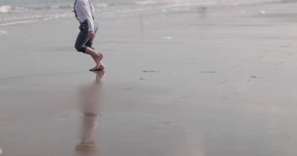 Barn leker på stranden och i havet — Stockvideo