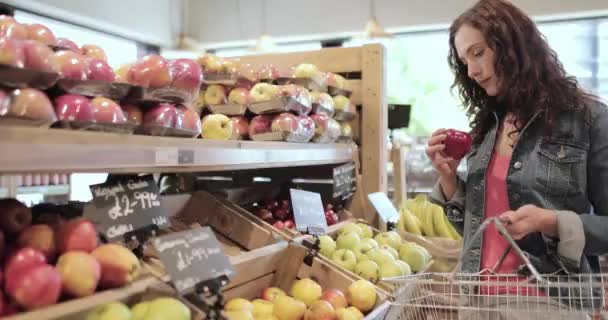 Női vásárló almákat vásárol egy élelmiszerboltban — Stock videók