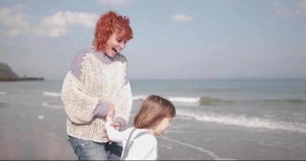 Mutter und Kind spielen im Herbst am Strand — Stockvideo