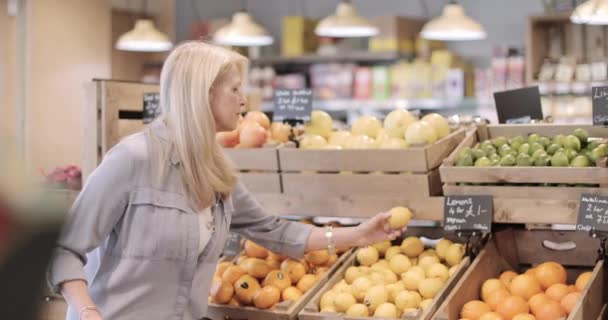 Старшая женщина покупает фрукты в продуктовом магазине — стоковое видео