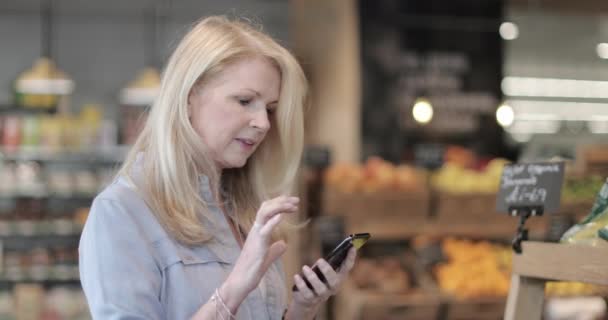 老年女性每周使用智能手机在杂货店购物 — 图库视频影像