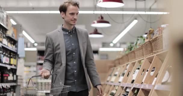 Дорослі чоловіки вибирають вино в продуктовій крамниці. — стокове відео