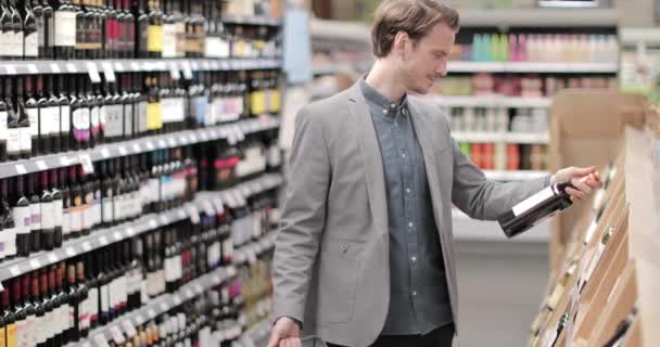 Adulto macho eligiendo vino en tienda de comestibles — Vídeos de Stock