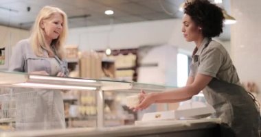 Satış asistanı bir şarküteride müşteriye hizmet ediyor.