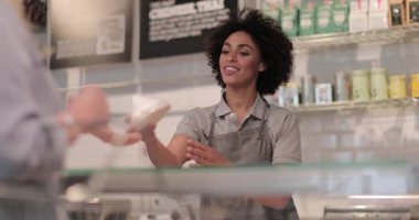 Satış asistanı bir şarküteride müşteriye hizmet ediyor.