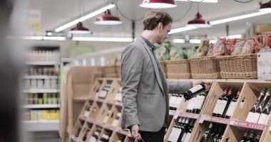 Yetişkin erkek markette şarap seçiyor.