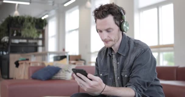 Jong volwassen mannetje smartphone gebruiken in een creatieve office — Stockvideo