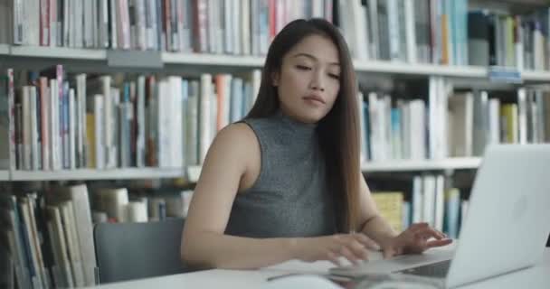 Asiática mujer trabajando en la biblioteca universitaria en portátil — Vídeos de Stock