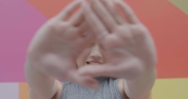 Asiatische junge erwachsene Frau enthüllt glückliches Gesicht vor buntem Hintergrund — Stockvideo