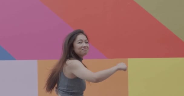 Asijská mladá ženská tančí a skáče šťastně před barvitým pozadím — Stock video