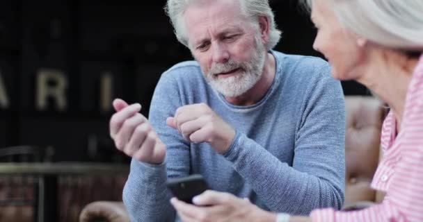 Starší dospělý pár v luxusním hotelovém salonku sdílení fotografií na chytrém telefonu — Stock video