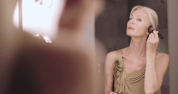 Взрослая женщина надевает макияж в зеркало и одевается — стоковое видео