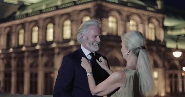 Pareja de adultos mayores abrazándose en la noche romántica frente a la ópera — Vídeos de Stock