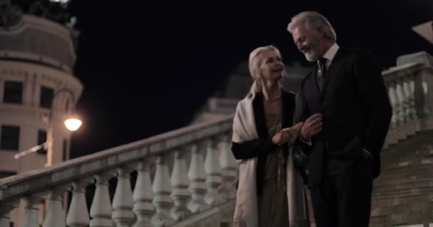 上了年纪的夫妇晚上穿着漂亮的衣服走下台阶 — 图库视频影像