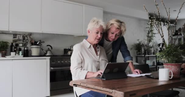 Mature lesbian couple looking at digital tablet together at home — Stock Video