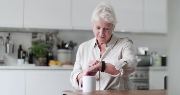 Reife erwachsene Frau blickt auf Smartwatch lächelnd — Stockvideo