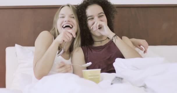 Девушки едят мороженое в постели и веселятся — стоковое видео