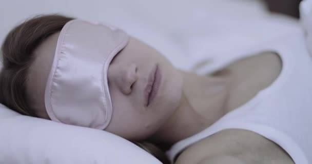Mooie jonge volwassen vrouw slapen in hotel slaapkamer met oogmasker — Stockvideo