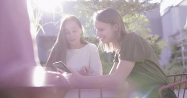Bir grup bayan arkadaş akıllı telefondan sosyal medyadan fotoğraflar paylaşıyor.