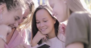 Bir grup bayan arkadaş akıllı telefondan sosyal medyadan fotoğraflar paylaşıyor.