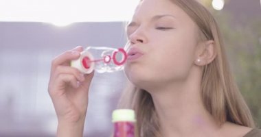 Yazın sabun köpüğü üfleyen güzel, genç bir kadın.