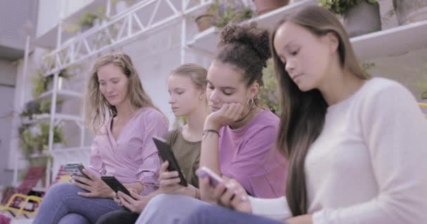 Группа женщин смотрит на экраны на смартфоне и не разговаривает — стоковое видео
