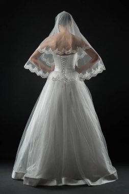 Uzun, güzel, beyaz bir gelinlik ve dantelli bir duvak içinde gelin. Siyah arkaplan