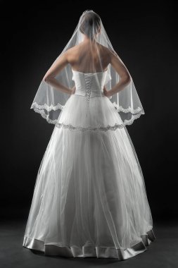 Uzun, güzel, beyaz bir gelinlik ve dantelli bir duvak içinde gelin. Siyah arkaplan