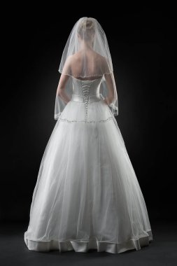 Uzun, güzel, beyaz bir gelinlik ve dantelli bir duvak içinde gelin. Siyah arkaplan