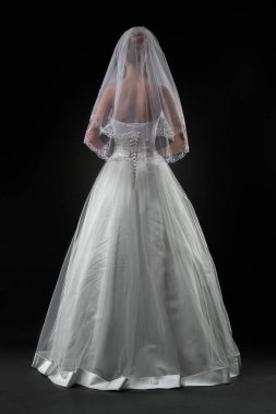 Uzun, güzel, beyaz bir gelinlik ve dantelli bir duvak içinde gelin. Siyah arkaplan