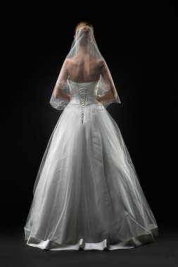 Uzun, güzel, beyaz bir gelinlik ve dantelli bir duvak içinde gelin. Siyah arkaplan